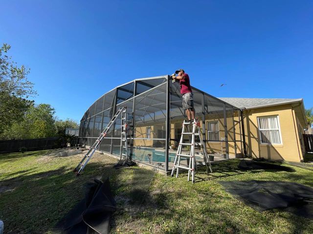Crew fitting new screen into a pool enclosure frame