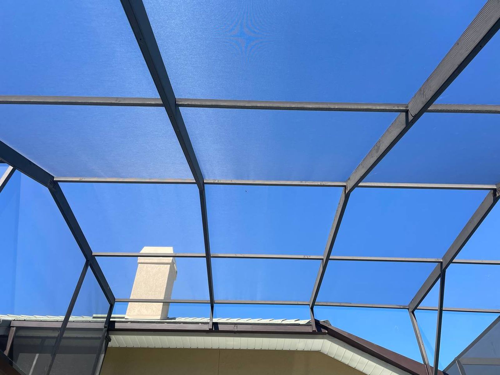 Looking up through a freshly rescreened pool cage into blue Florida sky
